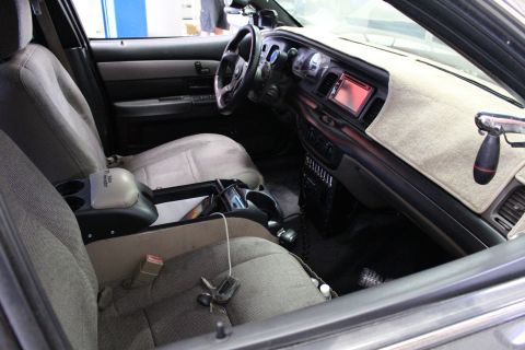 2003 Ford Crown Victoria - Interior of a sedan viewed from the passenger side, showing gray cloth seats, a column shifter and a fabric dash cover.