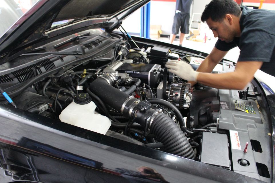 Mechanic working on the supercharged engine of a black car in a shop