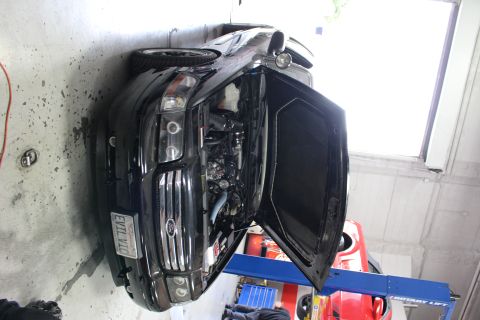 2003 Ford Crown Victoria - black Ford sedan with hood open in a garage next to a red car on a lift, showing an EVIL VIC front plate.