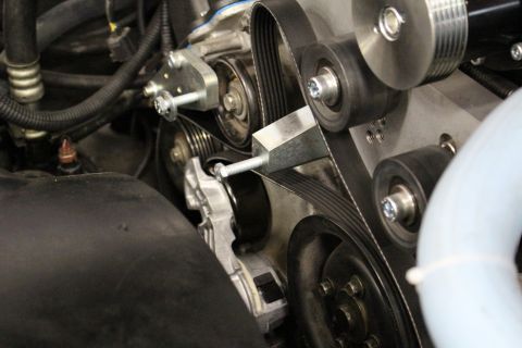 2003 Ford Crown Victoria - Close-up of a serpentine belt wrapping multiple pulleys with a mounting bracket and tensioner in an engine bay.