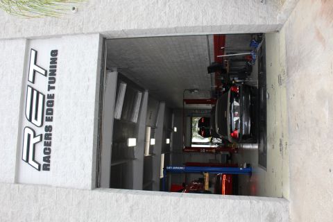 2003 Ford Crown Victoria - Bay door entrance under a Racers Edge Tuning sign, with a black sedan parked on the shop dyno.