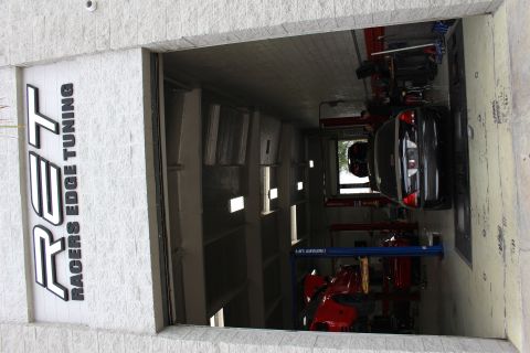 2003 Ford Crown Victoria - Shop entrance under a Racers Edge Tuning sign with a black sedan on a dyno and a red car on a lift.