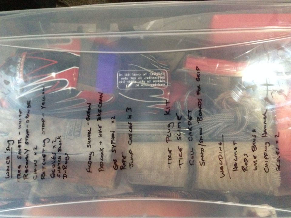 Contents of a plastic bag with handwritten labels including winch, shovel, tire plug kit, and welding gear