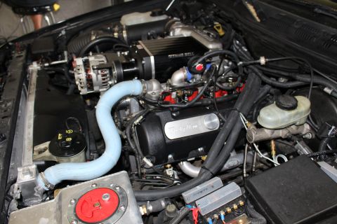 2003 Ford Crown Victoria - Engine compartment showing a Kenne Bell supercharger, Trick Flow valve cover, blue coolant hose and red fuel fill plate.
