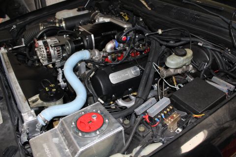 2003 Ford Crown Victoria - Engine compartment showing a Kenne Bell supercharger, Trick Flow valve cover, blue coolant hose and red fuel fill plate.