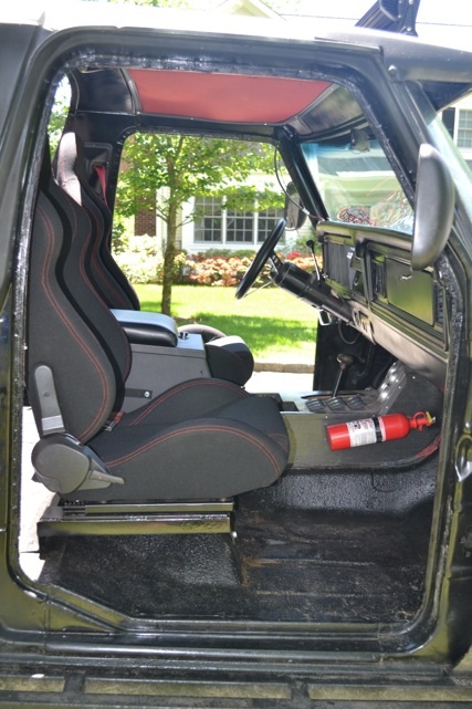 1979 Ford Bronco - The interior of a dark 1978 Ford Bronco is visible, racing seats and a fire extinguisher on the floor.