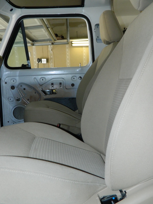 Interior of a vehicle with door panel removed, showing seats and exposed metal