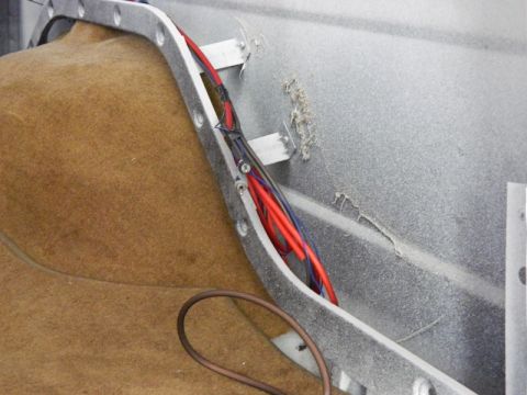 1979 Ford Bronco - Close-up view of a vehicle's interior wiring harness, showing red and blue wires secured by metal brackets.