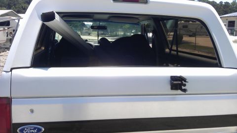 1994 Ford Bronco - The rear cargo area of a 1994 Ford Bronco is filled with items, including a long metal pole.