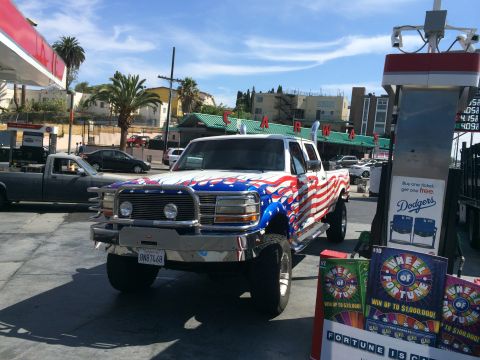 1968 Ford Mustang - A custom-painted truck with patriotic graphics sits at a gas station with lottery tickets displayed nearby.