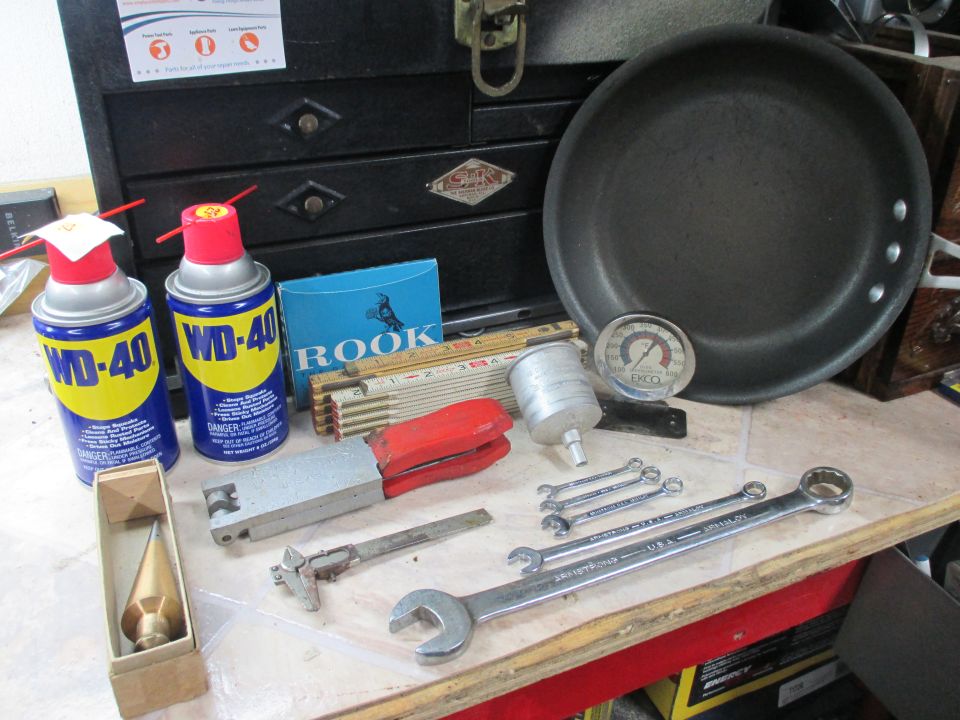Collection of tools including WD-40 cans, wrenches, a plumb bob, and a frying pan