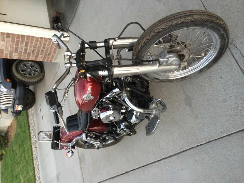 Red Harley-Davidson motorcycle with chrome V-twin engine and ape hanger bars parked on a driveway
