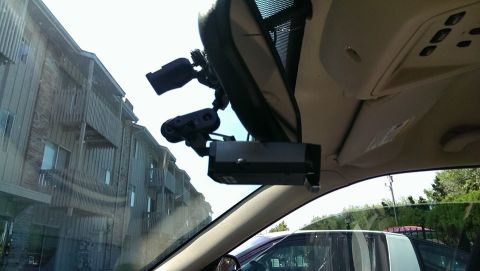 2000 Mercury Grand Marquis - Interior view of a vehicle showing mounted electronics and a reflection of apartment buildings.