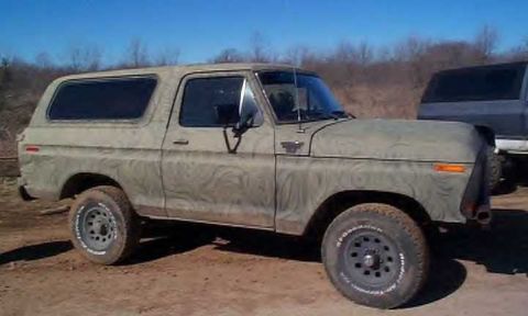1978 Ford Bronco - Full side profile of a tan two-door full-size Ford SUV with a removable hardtop, its paint swirled with dried mud from a trail run. It sits…