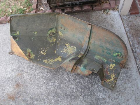 1946 Jeep Willys - This heavily rusted metal panel, possibly from a vehicle, sits on a concrete surface with some grass and bricks in the background.