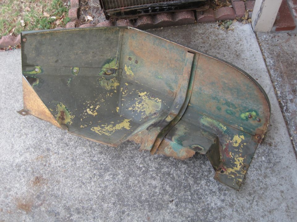 Rusted green and yellow metal panel on concrete. Supermotors.net logo in corner