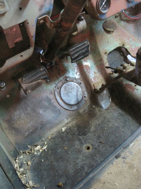 1946 Jeep Willys - The interior floor of a vehicle shows pedals, a circular cover plate, and debris.