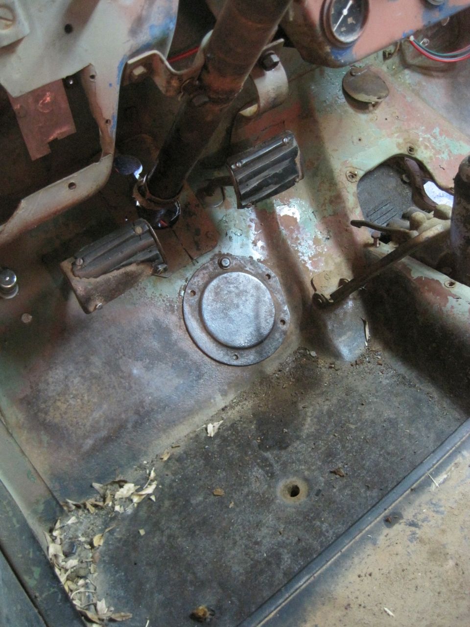 Floor pan and pedals inside an old vehicle. Looks like it needs work