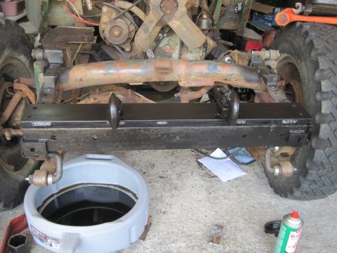 1946 Jeep Willys - Close-up of a Jeep's front axle and bumper assembly, showing mechanical components and repair supplies.
