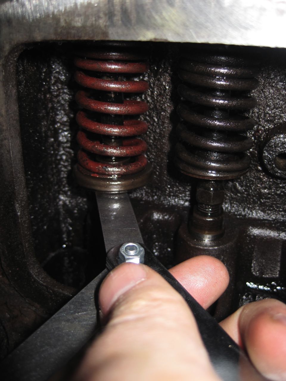 Feeler gauge being used to adjust engine valve spring