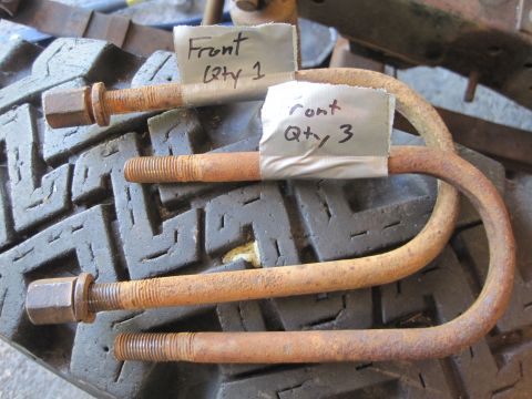 1946 Jeep Willys - Rusty U-bolts, labeled for front installation, sit on a tire tread.