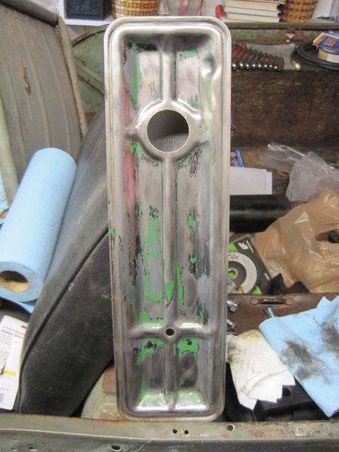 1946 Jeep Willys - A metal valve cover, showing signs of wear and chipped green paint, is displayed in a workshop setting.