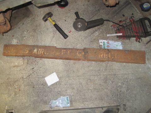 1946 Jeep Willys - A rusty metal beam, possibly from US Aircraft Co., lies on a concrete floor with tools nearby.