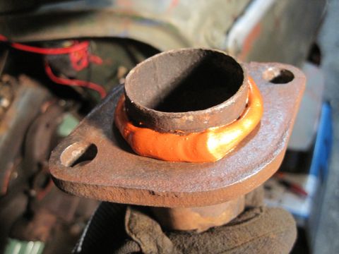 1946 Jeep Willys - Close-up of a rusty exhaust pipe flange with bright orange sealant applied.