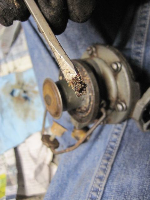 1946 Jeep Willys - Debris is being removed from a vehicle's distributor cap with a flathead screwdriver.