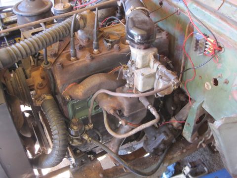 1946 Jeep Willys - The engine compartment of an older Jeep shows signs of wear and tear, with various components exposed.