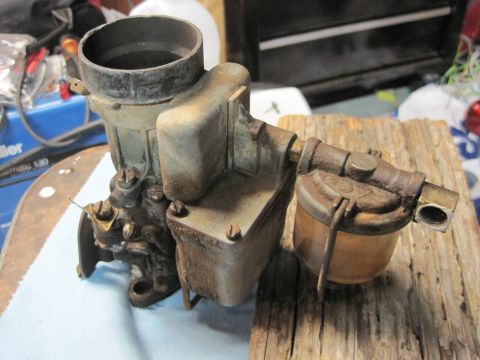 1946 Jeep Willys - Carburetor and fuel filter assembly, likely for an older vehicle, resting on wood.
