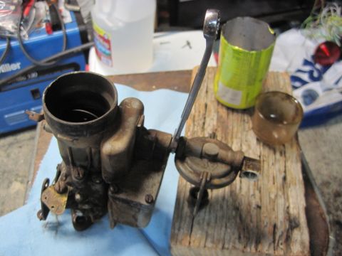 1946 Jeep Willys - A carburetor is shown on a workbench with tools and other items nearby.