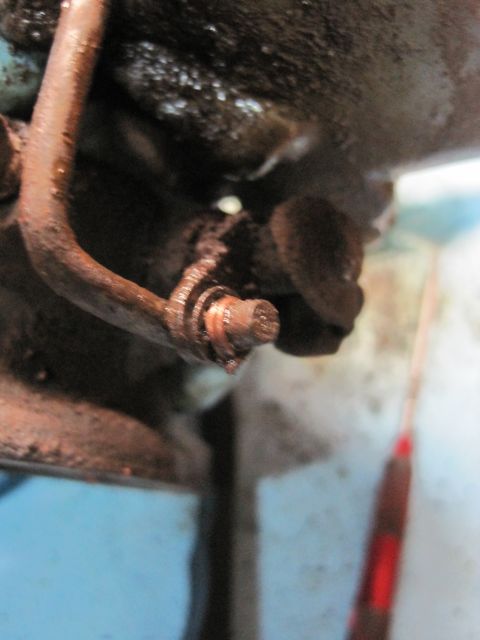 1946 Jeep Willys - A close-up view of a rusty engine part, possibly a fuel line connection, with a bolt and hose visible.