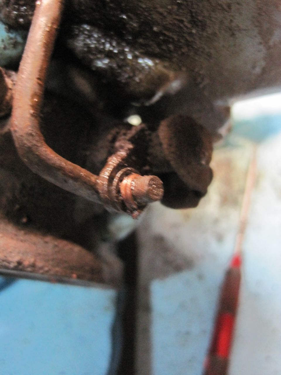 close-up of rusty engine component with a bolt and hose