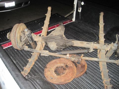 1946 Jeep Willys - Front axle assembly, leaf springs, and brake rotors are pictured in the bed of a pickup truck.