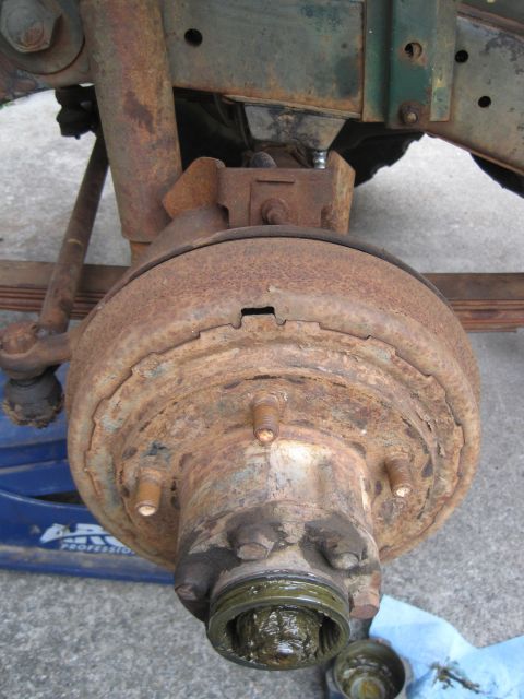 1946 Jeep Willys - Close-up of a heavily rusted front wheel hub and brake drum, showing grease around the spindle.