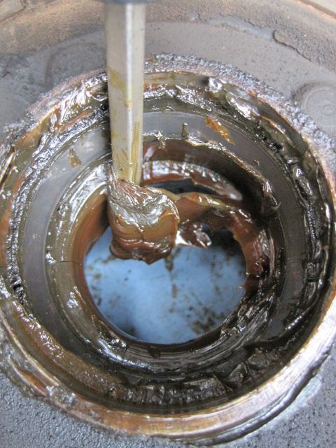 1946 Jeep Willys - A tool applies grease to a wheel bearing, likely during maintenance or repair.