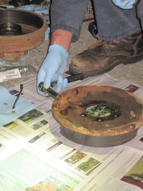 1946 Jeep Willys - Working on a rusty brake drum and hub assembly with tools and newspaper on the floor.