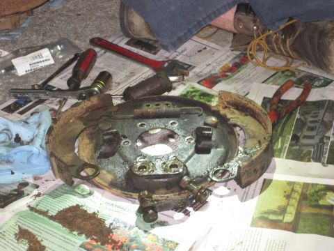 1946 Jeep Willys - A disassembled Jeep brake drum assembly and tools are spread out on newspapers, suggesting a repair or maintenance activity.