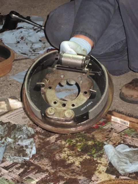 1946 Jeep Willys - A mechanic works on a brake drum assembly, showing the brake shoes and wheel cylinder during maintenance.
