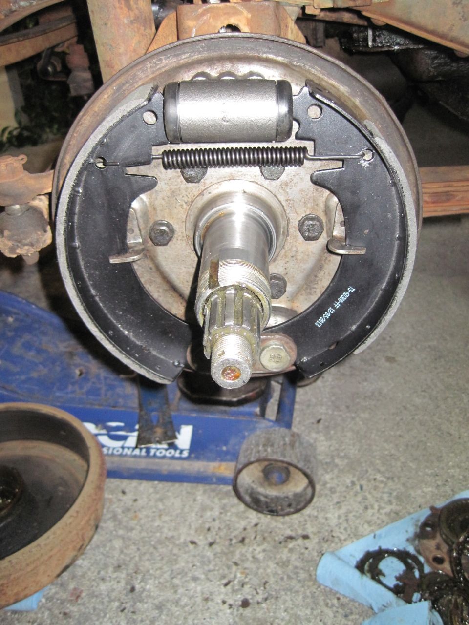 close-up of a vehicle's rear brake drum assembly with new brake shoes and wheel cylinder