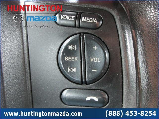 Close-up of steering wheel controls with buttons for voice, media, seek, and volume