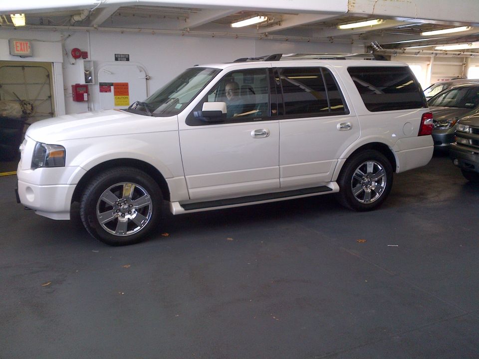 White Ford Expedition parked indoors, another vehicle visible to the right