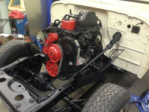 1986 Jeep Wagoneer - Engine bay of a Jeep chassis, a black engine with red pulleys and accessories.