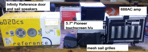 2002 Chrysler 300M - Various car audio components are laid out on a wooden surface, including speakers, a touchscreen head unit, and an amplifier.