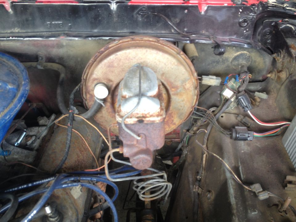 Rusty brake booster and master cylinder assembly with wiring harness in engine bay