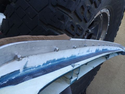 1995 Ford Bronco - Detail of a vehicle's soft top trim piece and a tire.