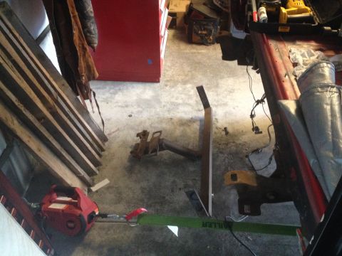 1978 Ford Bronco - A red winch is connected to a green strap, attached to a vehicle frame with a tow hitch in a cluttered garage.