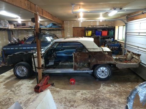 1964 Ford Fairlane - A 1964 Ford Fairlane convertible is disassembled in a garage, with a blue car parked behind it.