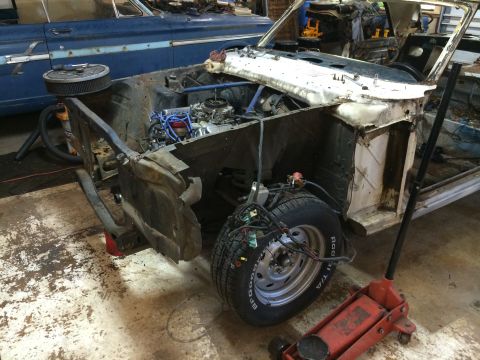 1964 Ford Fairlane - A partially disassembled 1964 Ford Fairlane sits in a workshop, with another blue car visible in the background.